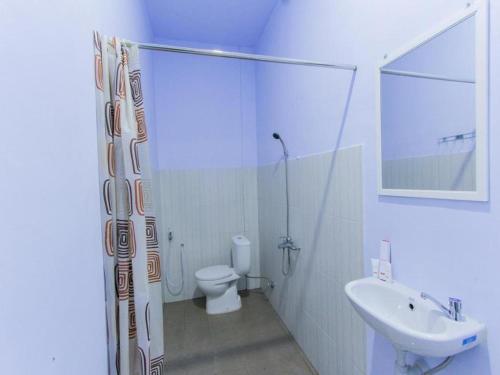 a white bathroom with a toilet and a sink at Hotel O Asipra House in Banyuwangi