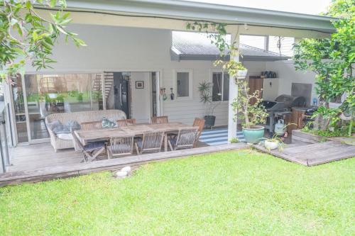 a patio with a wooden table and chairs on the grass at Relaxing Retreat in Terrigal in Terrigal