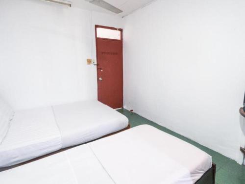 two beds in a small room with a door at OYO 89706 To-day Hotel in Sibu