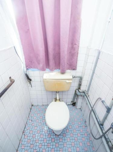 a bathroom with a toilet and a purple shower curtain at OYO 89706 To-day Hotel in Sibu