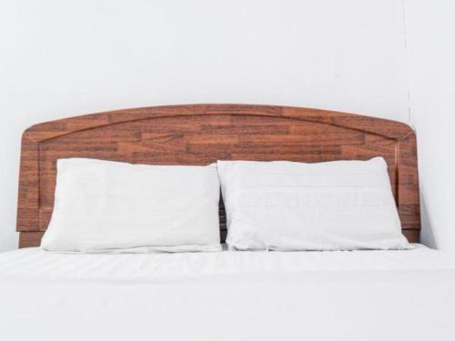 a bed with two white pillows and a wooden headboard at OYO 89706 To-day Hotel in Sibu