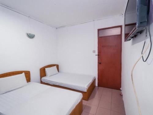 a room with two beds and a tv and a door at OYO 89706 To-day Hotel in Sibu