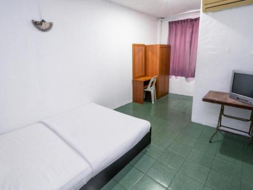 a bedroom with a bed and a desk and a television at OYO 89706 To-day Hotel in Sibu