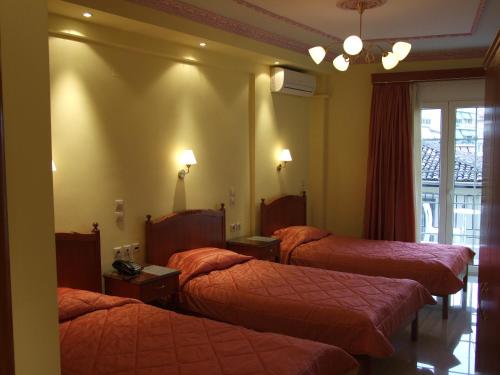a hotel room with three beds and a window at Hotel Avra in Kardítsa