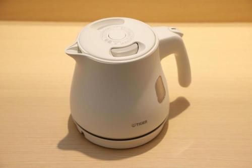 a white electric kettle sitting on a wooden table at KEIKYU EX INN Haneda Innovation City 2 minutes walk from HICity Exit of Tenkubashi Station in Tokyo