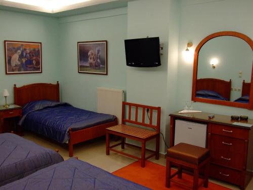 1 dormitorio con 2 camas, escritorio y espejo en Hotel Avra, en Karditsa