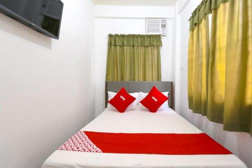 a small bedroom with a bed with red pillows at OYO 736 Jade Apartelle in Calamba