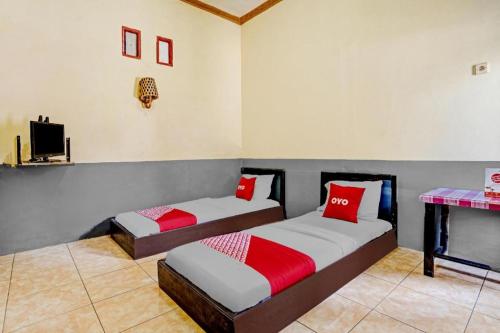 two beds with red pillows in a room at OYO 90405 Penginapan Sasti Kuningan in Kuningan
