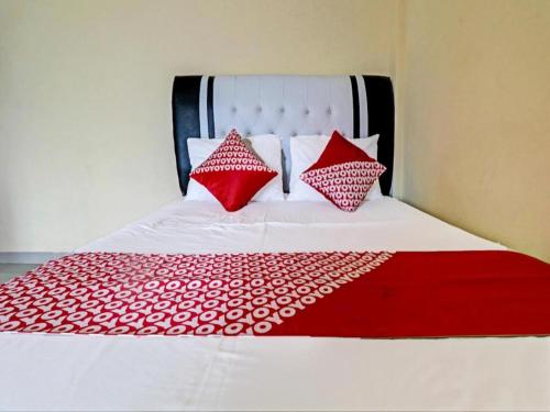a bed with red and white pillows on it at OYO 90945 Arizon Kost in Jambi