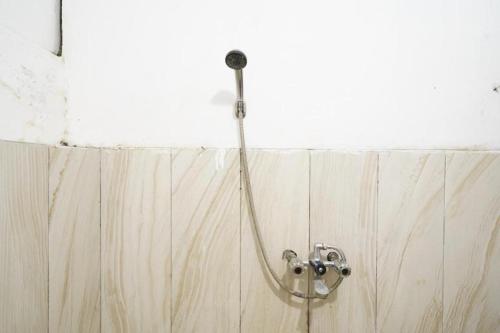 a shower with a hose attached to a wall at OYO 91546 Dewi Sudirman Homestay in Bandung