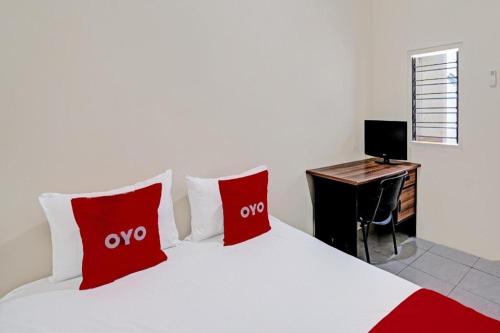 a bedroom with a bed with red pillows and a desk at Hotel O Wonoayu Residence Syariah in Sidoarjo