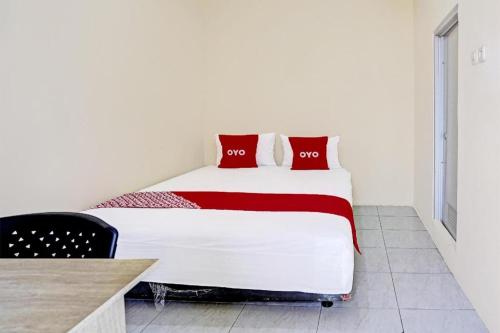 a bedroom with a large bed with red pillows at Hotel O Wonoayu Residence Syariah in Sidoarjo