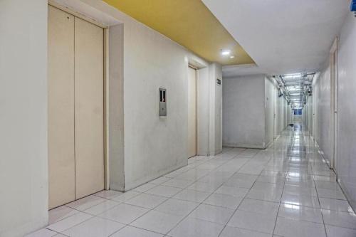 an empty hallway with white walls and white tile floors at Capital O 91820 S&a Collection 2 in Jakarta