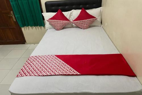 a bed with red and white pillows on it at OYO 91920 Pondok'ku Inn in Yogyakarta