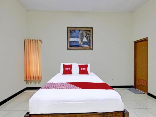 a bedroom with a large white bed with red pillows at OYO 91920 Pondok'ku Inn in Yogyakarta