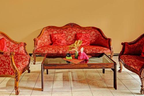 a living room with two red couches and a coffee table at Hotel O Homestay Simpang Panji Suroso Syariah in Malang