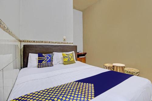 a bedroom with a bed with blue and yellow pillows at Hotel O Bagus Jaya Hotel in Semarang