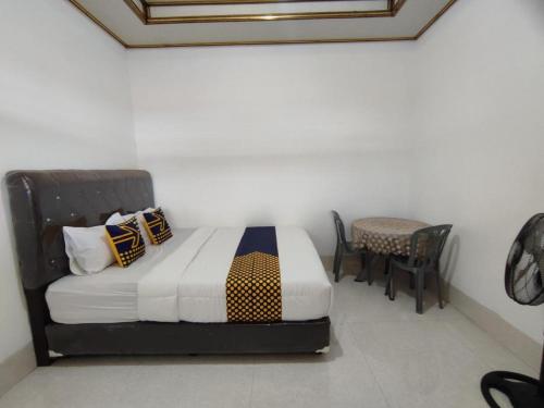 a bedroom with a bed and a table and chairs at Hotel O Wisma Sidosari Syariah in Bandar Lampung