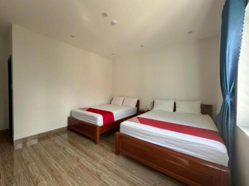 two beds in a room with white walls and wood floors at Motel Phuong Linh in Da Nang