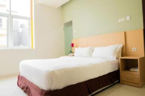 a bedroom with a large white bed with a window at Life Hotel Soekarno Hatta Makassar in Makassar