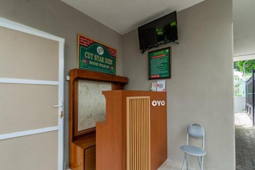 a room with a tv on the wall and a chair at Homely Syariah in Kediri