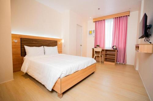 a bedroom with a bed and a desk and a table at JVJ HOTEL in Batangas City