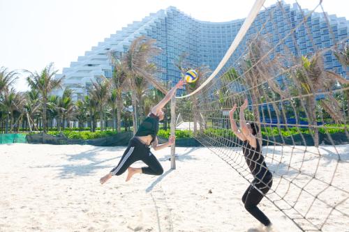 two people playing volleyball on the beach at The Empyrean Cam Ranh Beach Resort in Cam Ranh