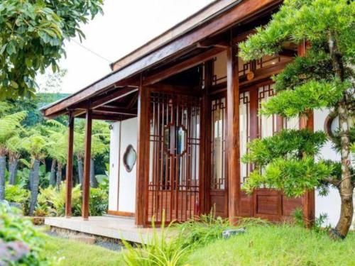 a wooden house with a porch in a garden at Jun's Home in Buon Ma Thuot