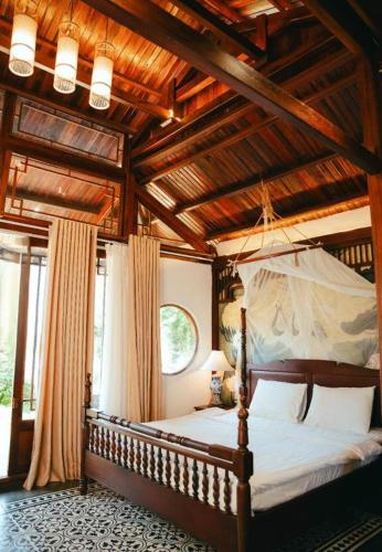 a bedroom with a canopy bed with wooden ceilings at Jun's Home in Buon Ma Thuot