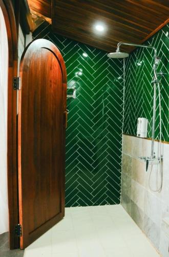 a bathroom with a wooden door and a green wall at Jun's Home in Buon Ma Thuot