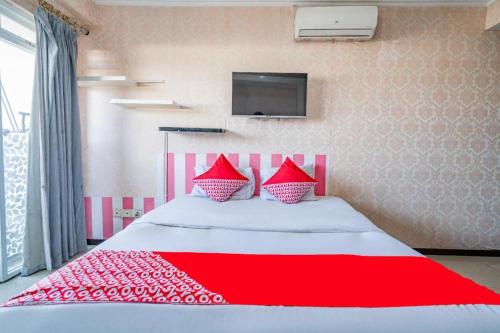 a red and white bed with red pillows on it at OYO 94150 Gateway Apartment Pasteur By Eldian in Bandung