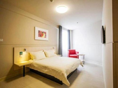a bedroom with a bed and a red chair at Jinjiang Inn Luoyang Nanchang Road Wangfujing in Luoyang
