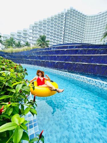 a woman riding on an inner tube in a swimming pool at The Empyrean Cam Ranh Beach Resort in Cam Ranh