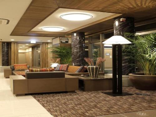 a living room with a couch and some plants at Hotel Sunoak Kashiwanoha in Kashiwa