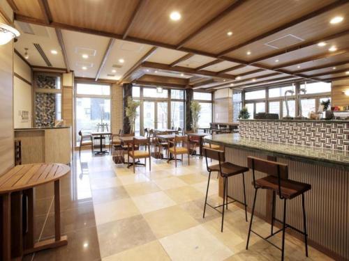 a restaurant with a bar and tables and chairs at Hotel Sunoak Kashiwanoha in Kashiwa