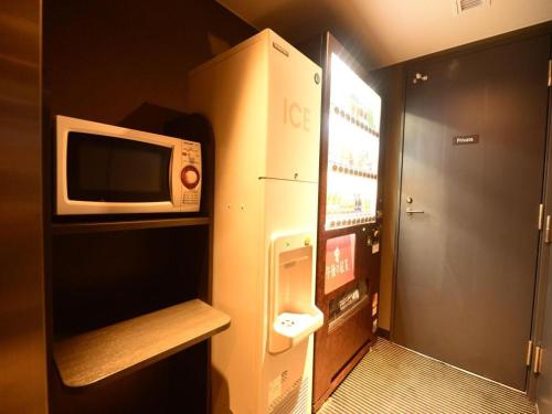 a small bathroom with a microwave and a refrigerator at APA Hotel Chiba Inzaimakinohara-Ekimae in Narita