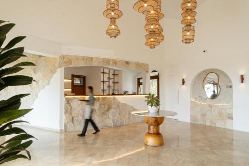a woman walks through a lobby with a table and chandeliers at Arpana Luxury Private Pool Villas in Jimbaran