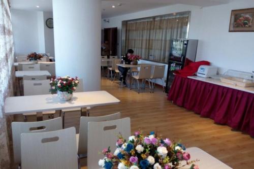 a room with tables and chairs with flowers on them at GreenTree Inn Geermu Walking Street Business Hotel in Golmud