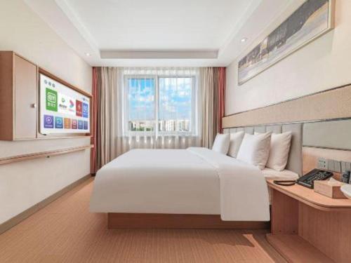 a bedroom with a large white bed and a window at GreenTree Inn Geermu Walking Street Business Hotel in Golmud
