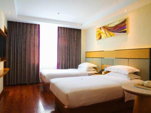 a hotel room with two beds and a table at GreenTree Inn Geermu Walking Street Business Hotel in Golmud