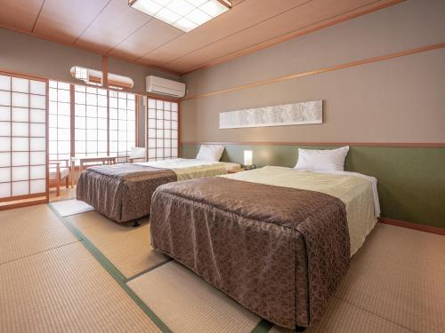 two beds in a room with windows at Yumoto Kanko Hotel Saikyo in Nagato