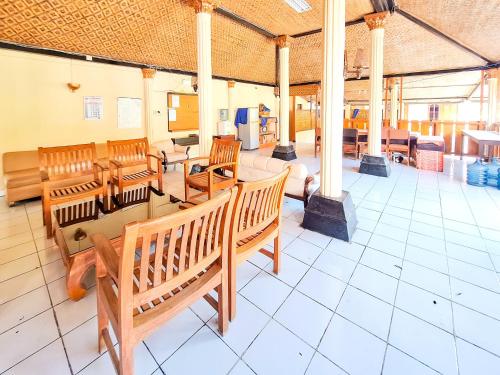 a large room with wooden benches and tables at Hotel Family Syariah 1 Parangtritis RedPartner in Parangtritis