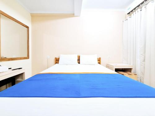 a bedroom with a large bed with a blue blanket at Hotel Family Syariah 1 Parangtritis RedPartner in Parangtritis
