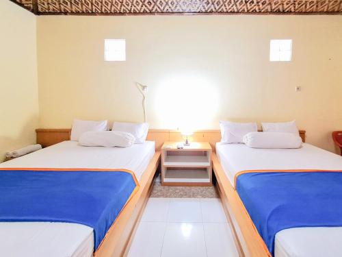 two twin beds in a room with a table at Hotel Family Syariah 1 Parangtritis RedPartner in Parangtritis