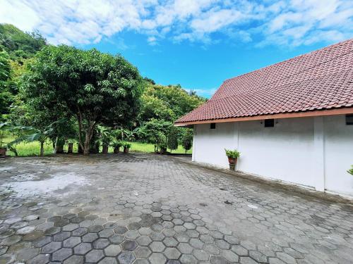a stone driveway next to a white building with trees at Hotel Family Syariah 1 Parangtritis RedPartner in Parangtritis