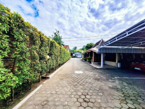 a cobblestone street next to a building and a hedge at Hotel Family Syariah 1 Parangtritis RedPartner in Parangtritis