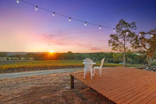 a couple of white plastic chairs sitting on a wooden deck at Vineyard Farmstay at Vista Fiano in Clare