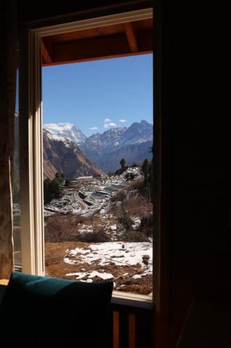 a window with a view of a snowy mountain at The Auli Meadows in Joshīmath