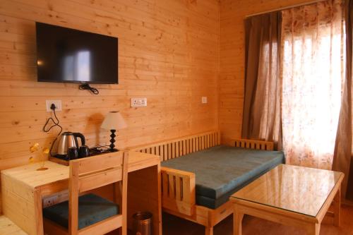 a room with a bed and a desk and a tv at The Auli Meadows in Joshīmath