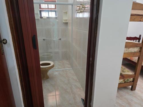a bathroom with a toilet and a glass shower at Peruíbe lazer in Peruíbe